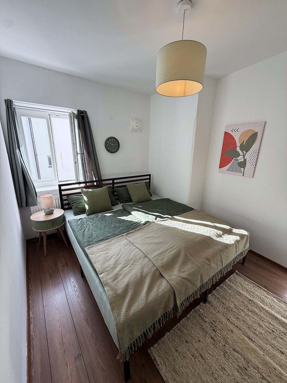Bedroom, upright view of the bed with the bedside table and lamp by the window
