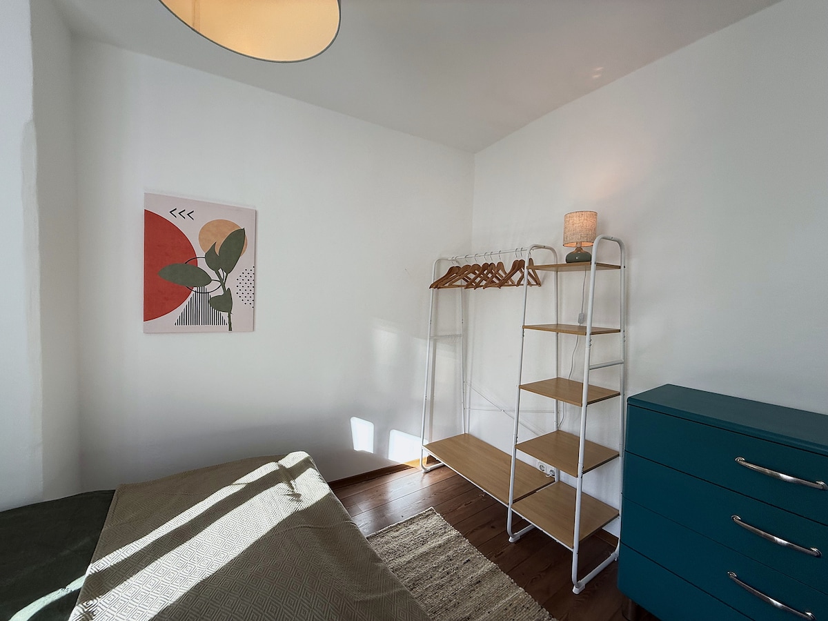 Clothes rail with hangers, shelves and the blue chest of drawers in the bedroom
