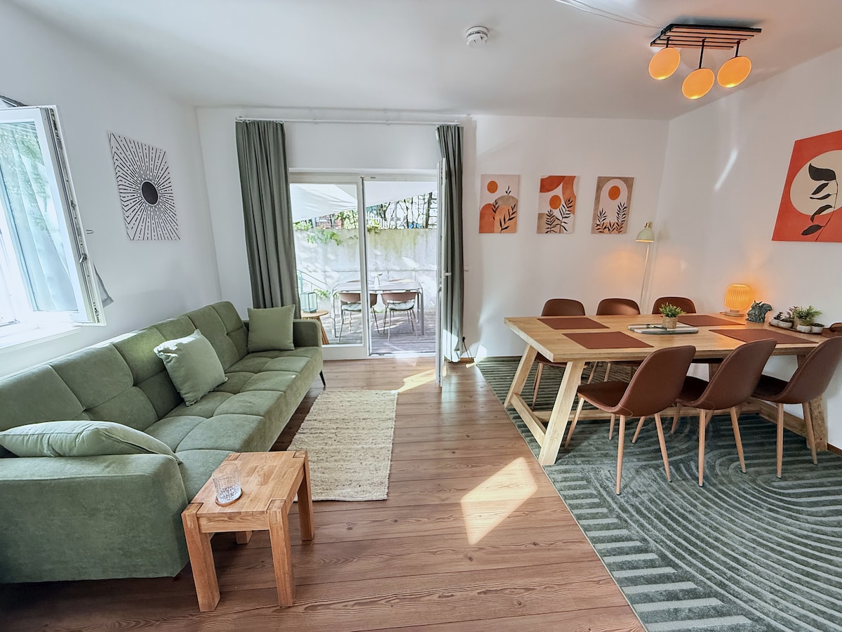 The open kitchen and dining area with the sofa bed, the 2 m wooden table and the door to the terrace