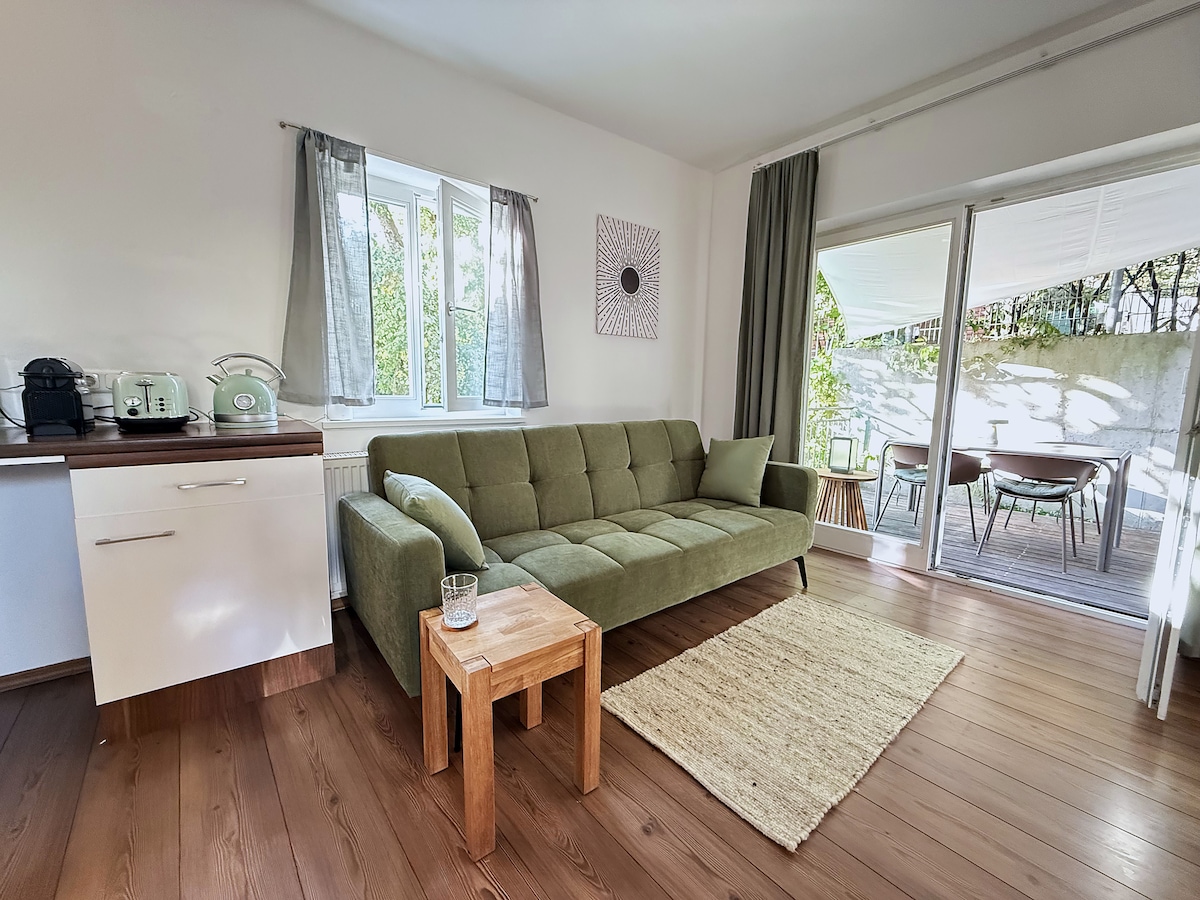 Nespresso machine, toaster and kettle on the kitchen counter, the terrace door open beside the sofa